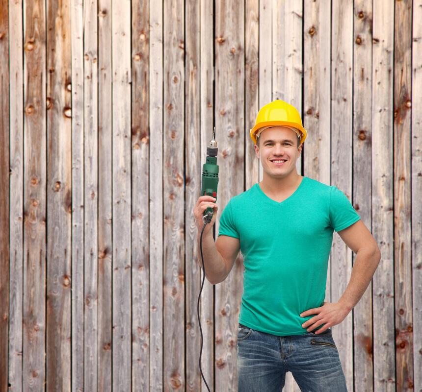 handyman holding a drill with fence background 